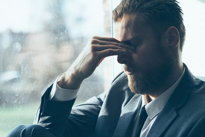 Sad man looks depressed and covers his eyes